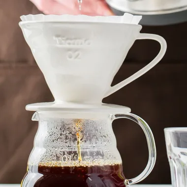 Hot water poured from a steel kettle over a pour-over dripper