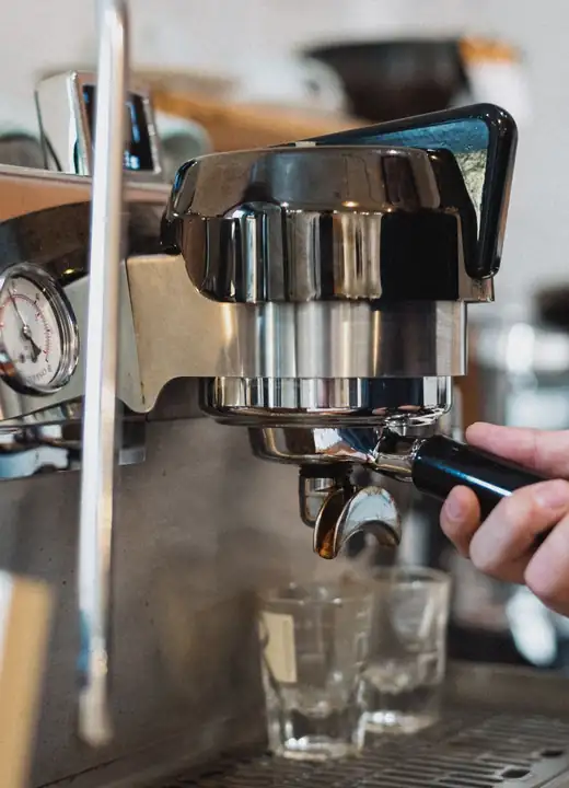 A wooden hand grinder with coffee beans around it